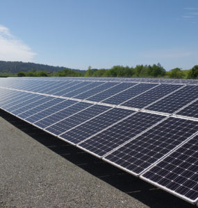 The array reflects sun, with low hills and blue sky beyond.