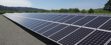 The array reflects sun, with low hills and blue sky beyond.