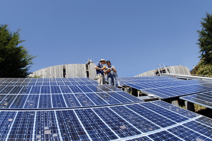 Two students discuss testing equipment while standing amidst the Trinidad array modules.