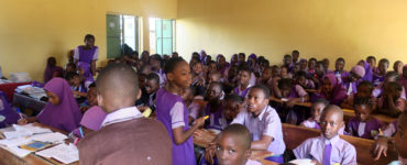A full class of students works at their desks.