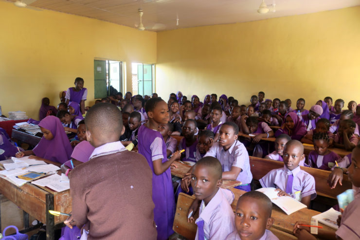 A full class of students works at their desks.