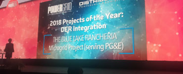 A presenter stands against the award screen at the DistribuTECH conference.