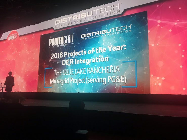 A presenter stands against the award screen at the DistribuTECH conference.