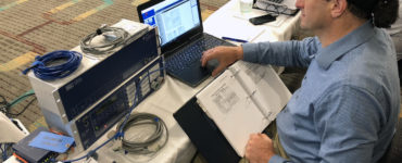 Dave Carter sits at a laptop connected to SEL equipment.