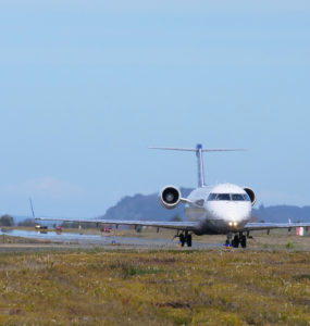 A plane moves along the runway, with Trinidad, CA in the distance
