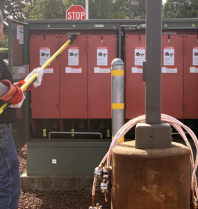 An electrician removes fuse covers using a safety pole