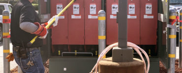 An electrician removes fuse covers using a safety pole