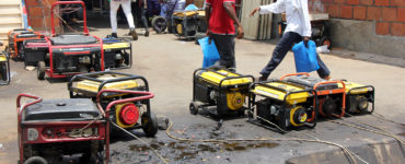 Men walk past an array of generators which are leaking fuel