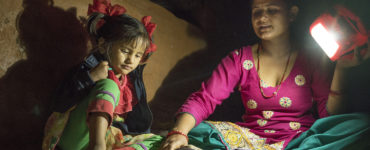 Ambika Parajuli holds a solar lamp to help her four year old daughter do homework.