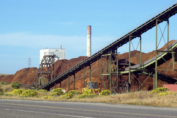 View of biomass pile and smokestack