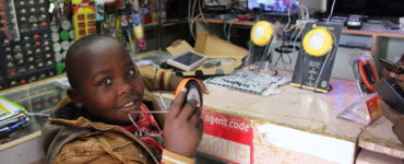 A child holds a solar product while standing at a store counter
