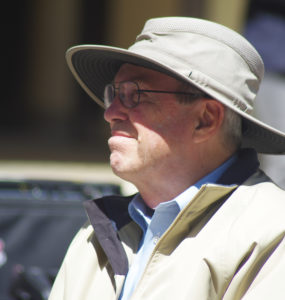 A man in a hat stands in the sun