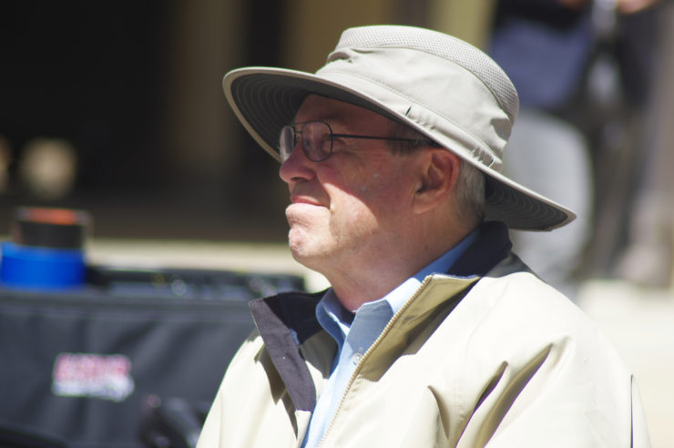 A man in a hat stands in the sun
