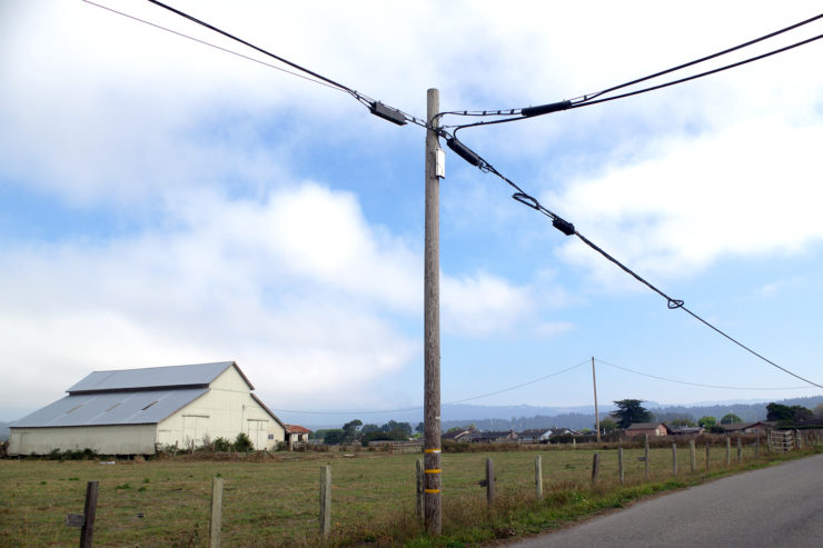 A utility pole in the foreground, with a barn in the background