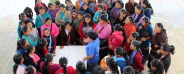 Over 50 women gather in a close circle to listen to a speaker