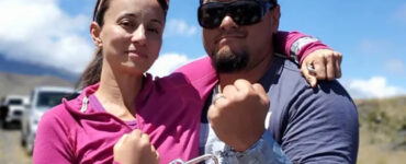 Two people stand with one arm around each other's shoulder and the other wrists locked together