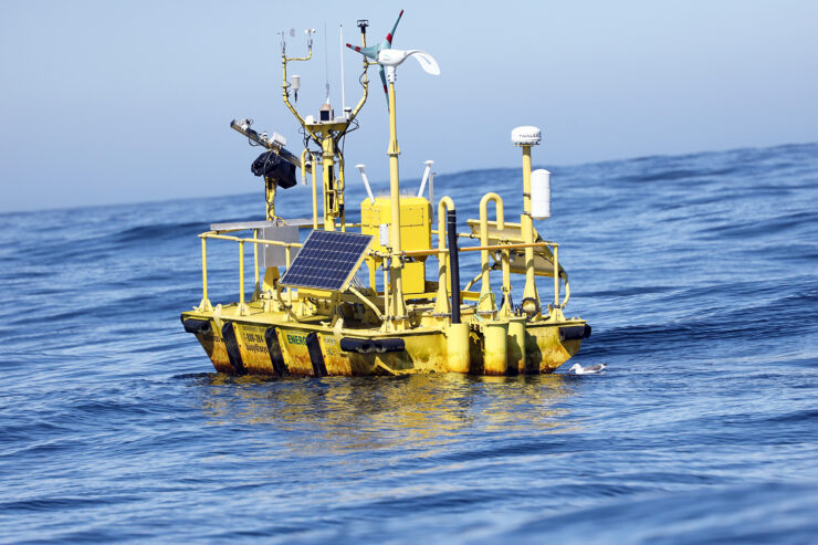 A yellow buoy with multiple sensors floats in open sea