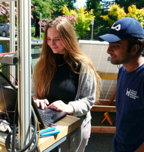 Students stand at a computer, operating a solar water pump