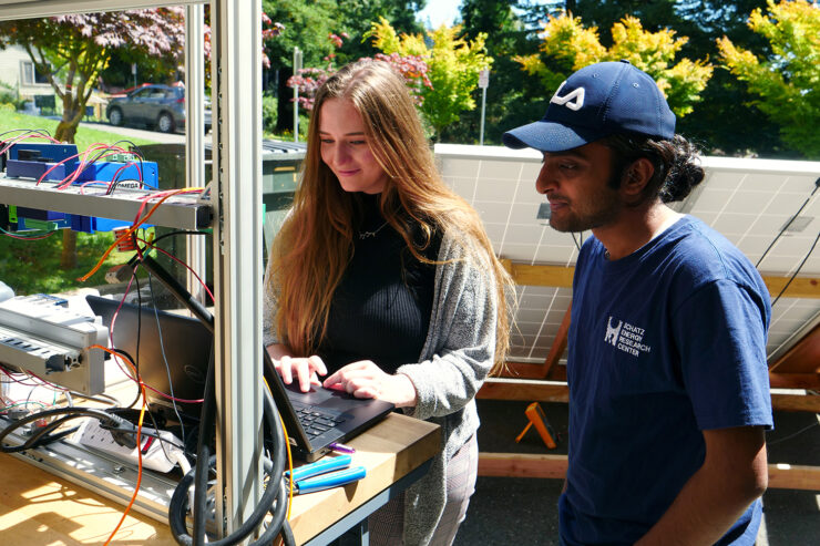 Students stand at a computer, operating a solar water pump